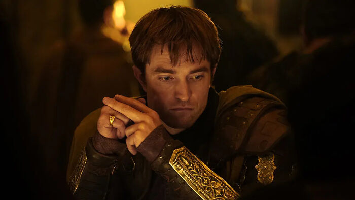Robert Pattinson parece pensativo, usando uma armadura ornamentada e um anel de ouro. Os fãs compartilham reações brutais ao seu novo filme.