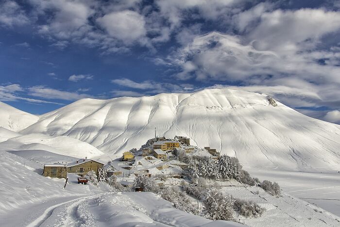 Snowy hillside village beneath white mountain stunning snowy mountain views