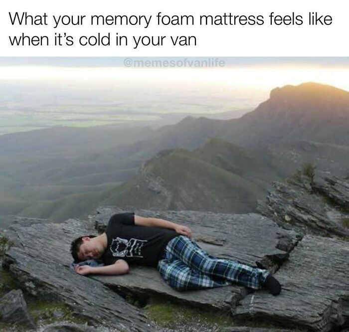 A man sleeping on a cold rock with mountains in the background, representing the reality of living out of a van.