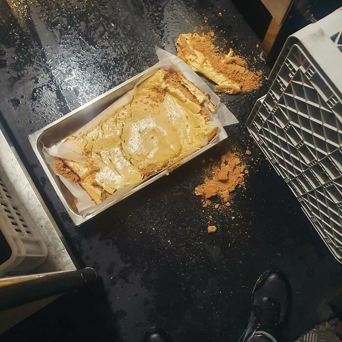 Baked dessert fallen out of pan with crumbs scattered on black surface