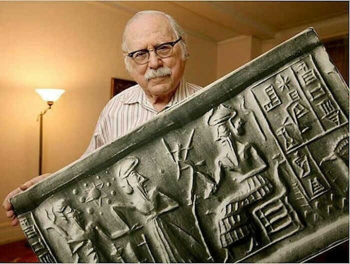 Man displaying ancient artifact with cuneiform and figures