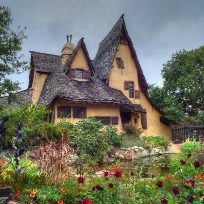 Unique fairy tale style house surrounded by flowers and greenery