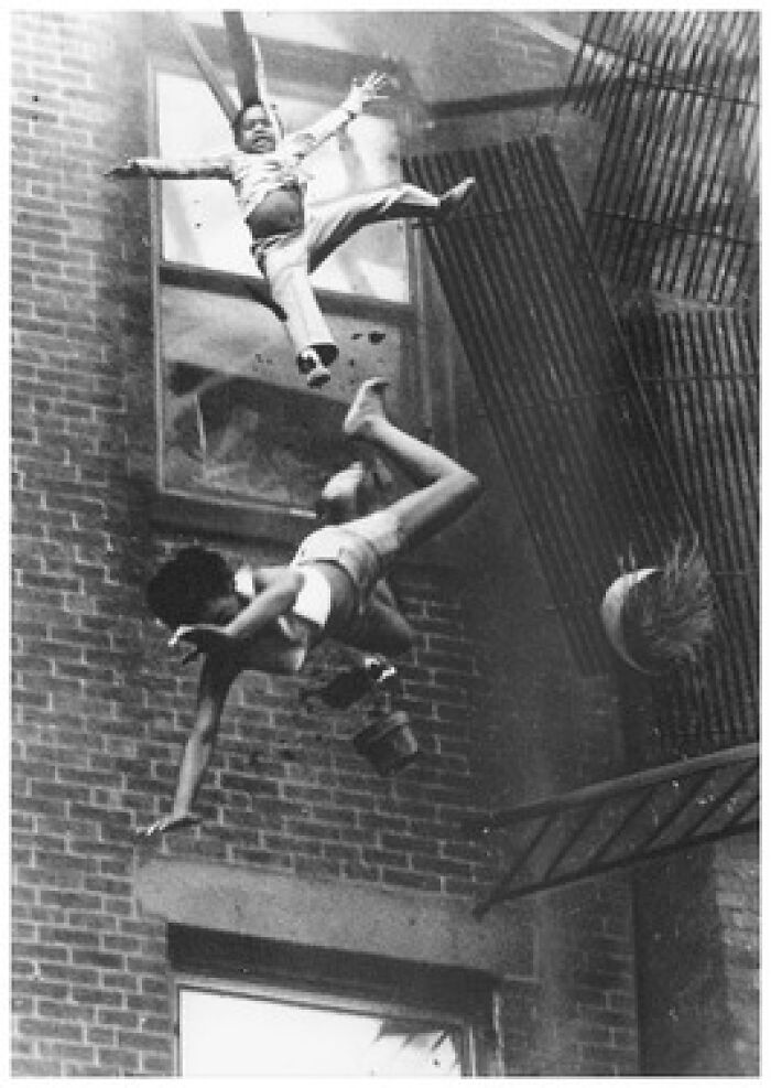 Old black and white photo of children falling from building fire escape