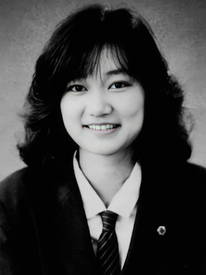 Black and white photo of a smiling young woman in a suit and tie, evoking disturbing d***h stories.
