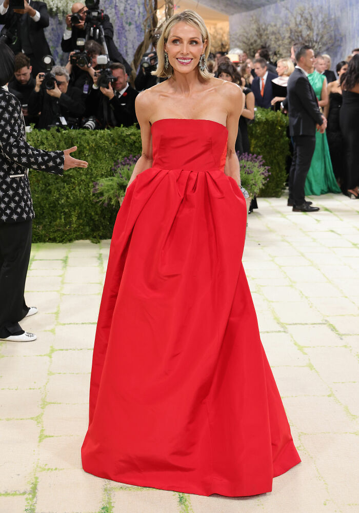 A woman in a strapless red gown smiles, showcasing one of the most jaw-dropping outfits from the MET Gala.