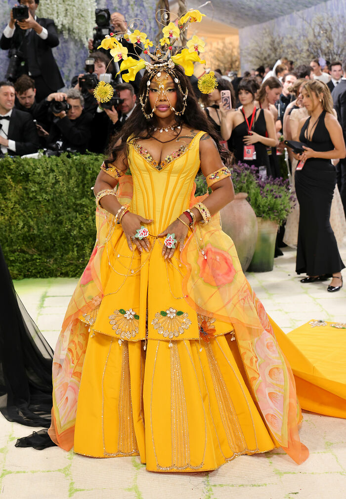 Jaw-dropping outfit from the 2026 MET Gala. A person in a vibrant yellow gown, ornate headpiece, and jewelry.