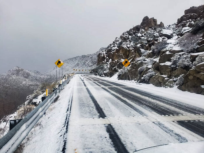 Snow covered mountain road with rocky cliffs and winter landscape