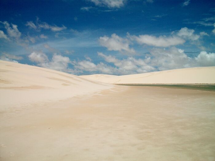 Wide sandy desert with blue sky and scattered clouds