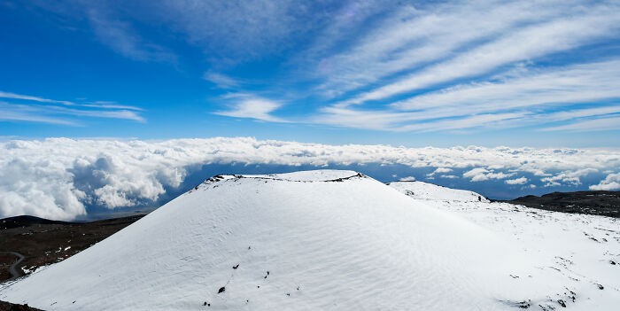 Snow-covered mountain peak under bright blue sky and clouds