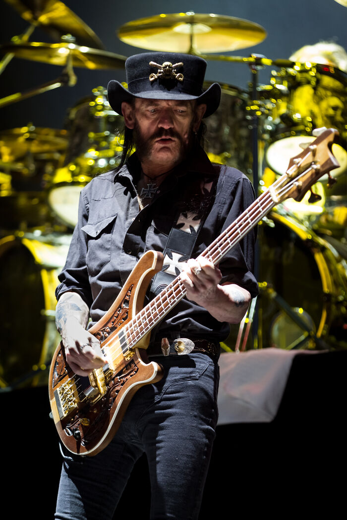 Lemmy Kilmister from Motörhead on stage, bass in hand, an iconic rock 'n' roll figure amidst glitches in the matrix.