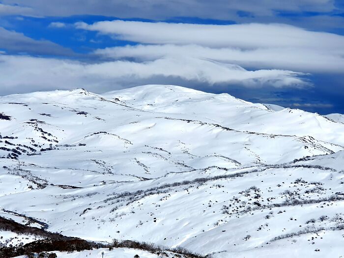Snow-covered mountain range with dramatic clouds stunning winter views