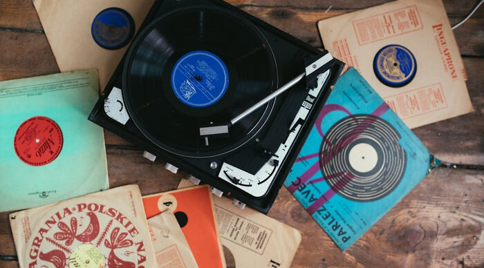 A vintage record player with various old records scattered on a wooden table, evoking a feeling of nostalgia.