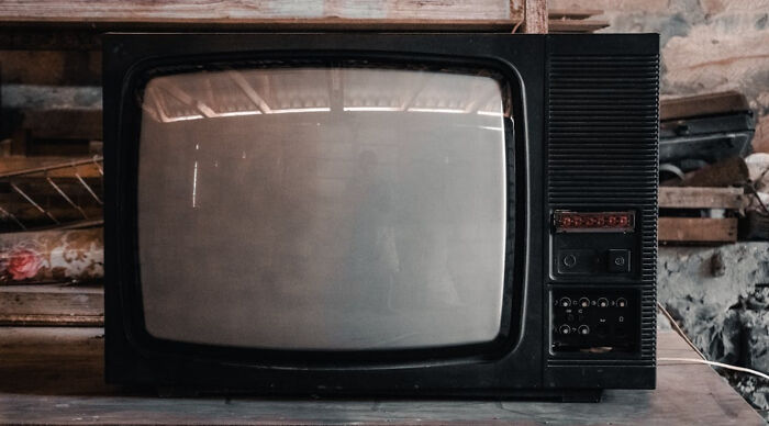 A vintage black CRT TV, evoking childhood memories, rests on a wooden surface against a cluttered background. How nostalgic are you?