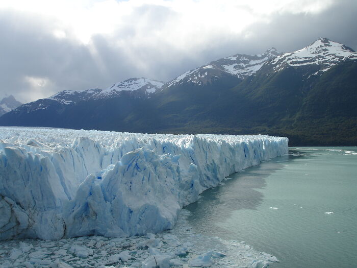 Massive glacier near mountain range under cloudy sky
