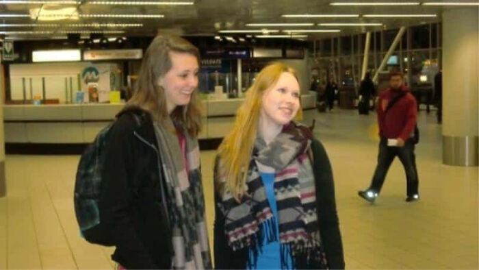 Two young women smiling and talking in a public indoor space in creepy photos