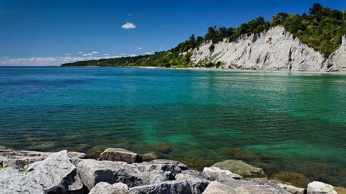Clear turquoise lake with rocky shoreline and scenic cliff views