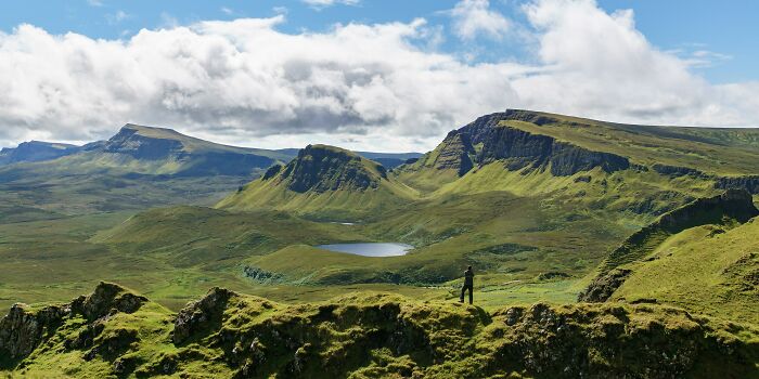 Traveler enjoying panoramic stunning views of green mountains and a small lake