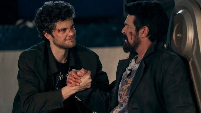 Hughie and Billy Butcher holding hands, both injured, in The Boys Finale, exploring character's fate.