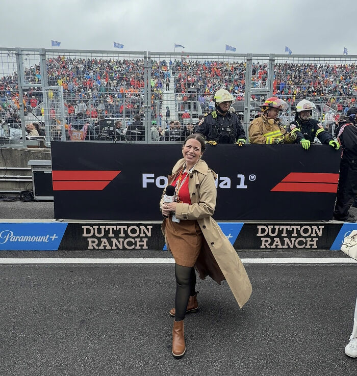 Female reporter standing in front of a Formula 1 race crowd holding a microphone