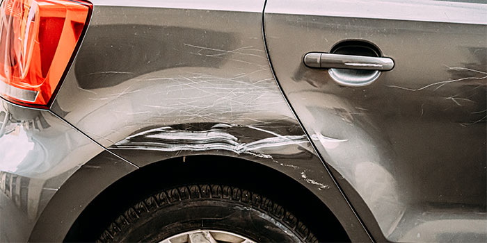 Scratched and dented car with visible damage on rear side