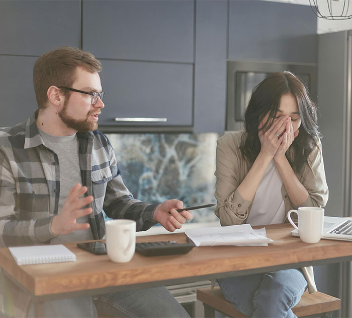 Man and woman arguing with bills and calculator at wooden table