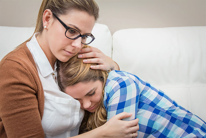 Woman consoling a teenage girl in emotional family conflict