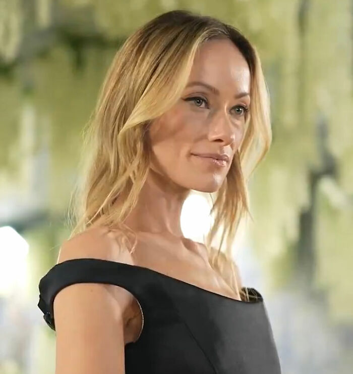 Olivia Wilde, com longos cabelos loiros e vestido preto com ombros largos, no Met Gala. Preocupação do ventilador de combustível.