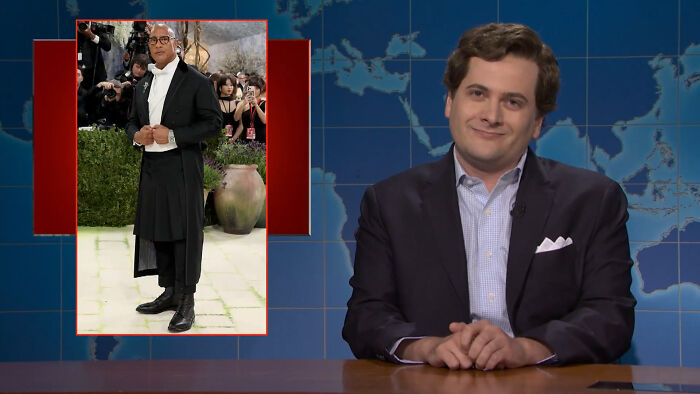 A man in a suit jacket and blue shirt smiles, with an image insert of a person in Met Gala outfit, evoking the Statue of Liberty in a Burqa discussion. A man in a suit jacket and blue shirt smiles, with an image insert of a person in Met Gala outfit, evoking the Statue of Liberty in a Burqa discussion.