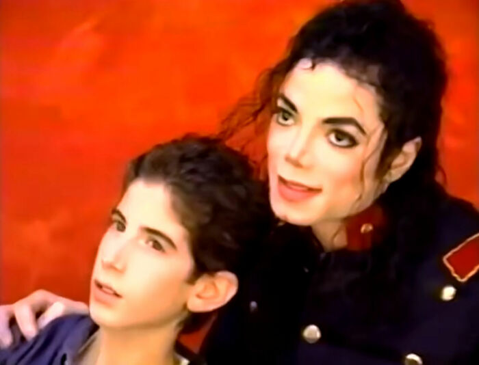Michael Jackson with a young boy, smiling. Accusations from his siblings are highlighted in a 60 Minutes interview.