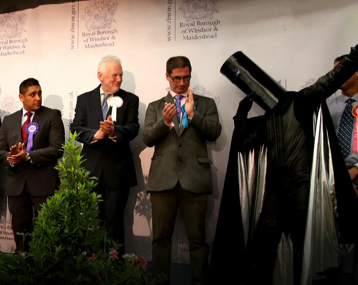 Political event with people clapping and a person in a black costume raising arm