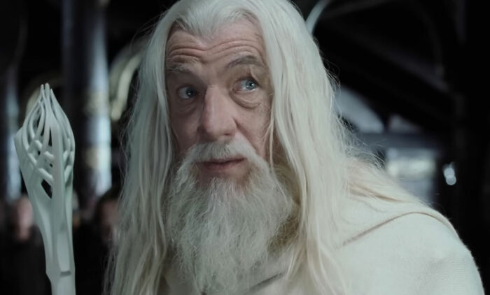 Close-up of Gandalf in white robes, holding his staff. The Gandalf vs. Dumbledore debate continues.
