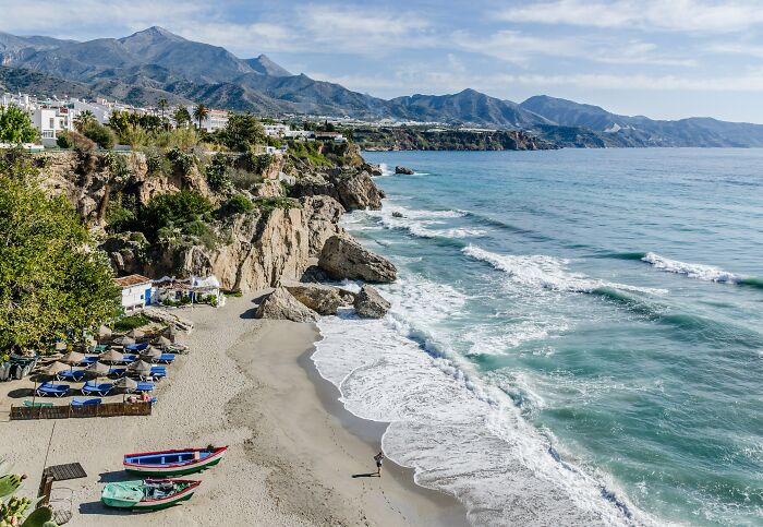 Coastal beach with rocky cliffs and waves under clear sky
