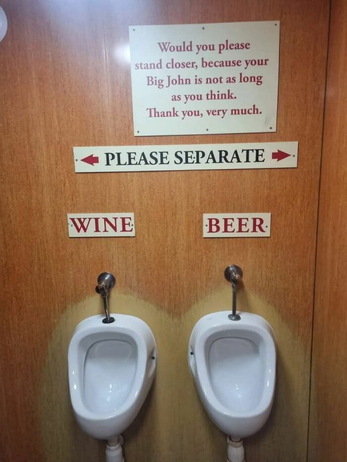 Absurd sign above urinals humorously separating wine and beer users