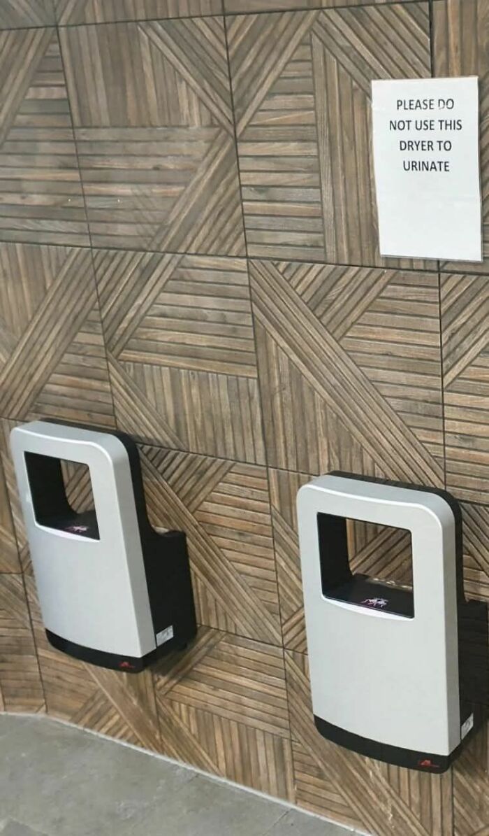 Sign warning not to urinate on hand dryers in restroom