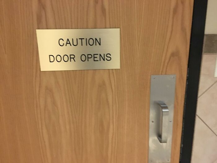 Caution door opens sign on wooden door