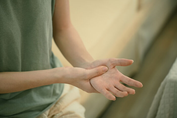 Person holding their hand in pain. This image relates to health warning signs and Routine Cancer Screening.