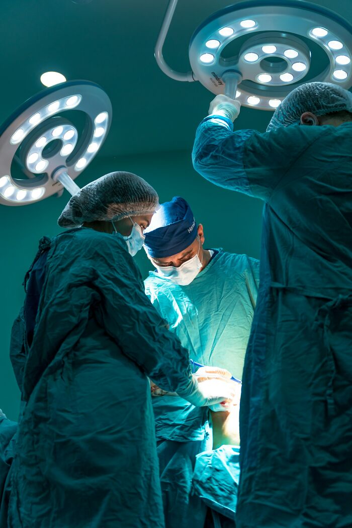 Surgeons performing operation under bright lights in operating room