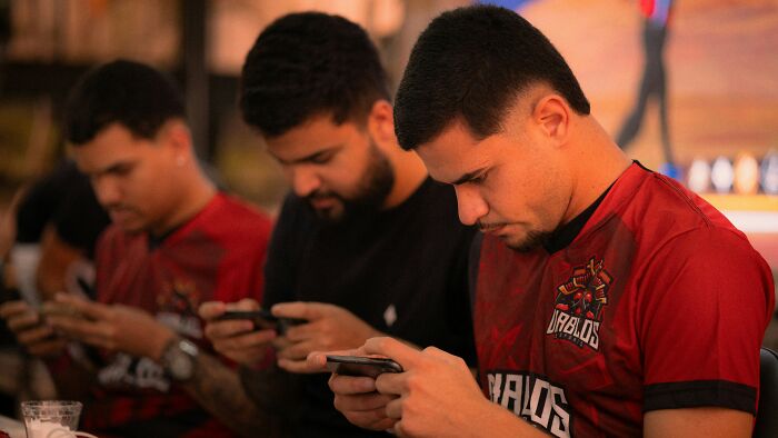 Three Gen Z men, engrossed in their phones, highlighting a common Gen Z behavior.