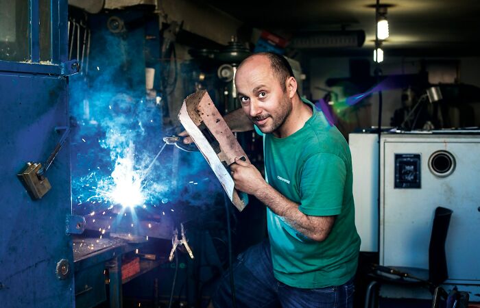 Man welding in workshop illustrating economic labor and industry