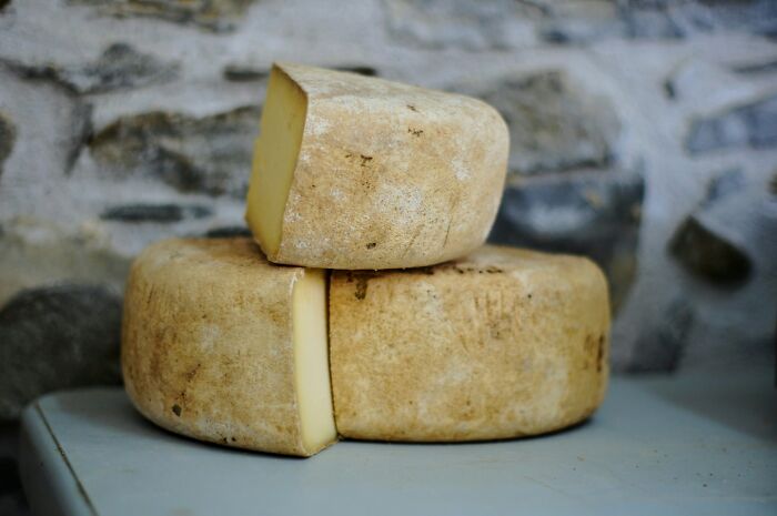 Wheels of aged cheese stacked against a rustic stone background