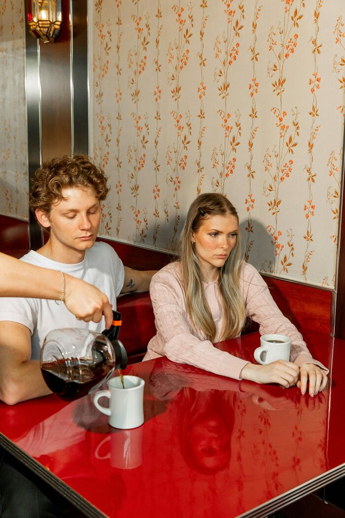 A person pours coffee for a man and a woman in a diner booth. Routine Cancer Screening.