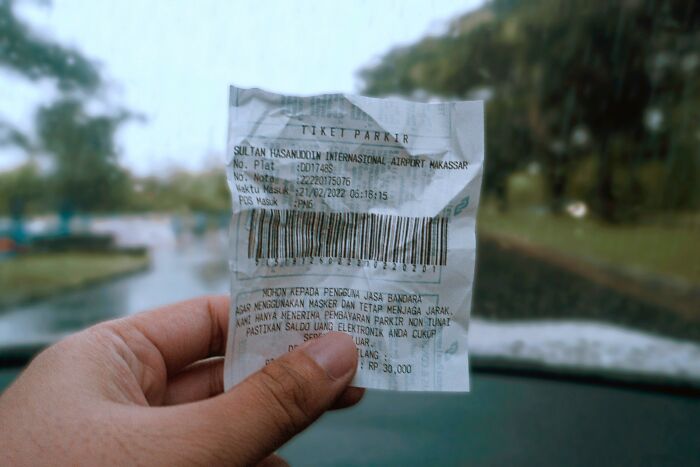 Hand holding crumpled parking ticket receipt in vehicle