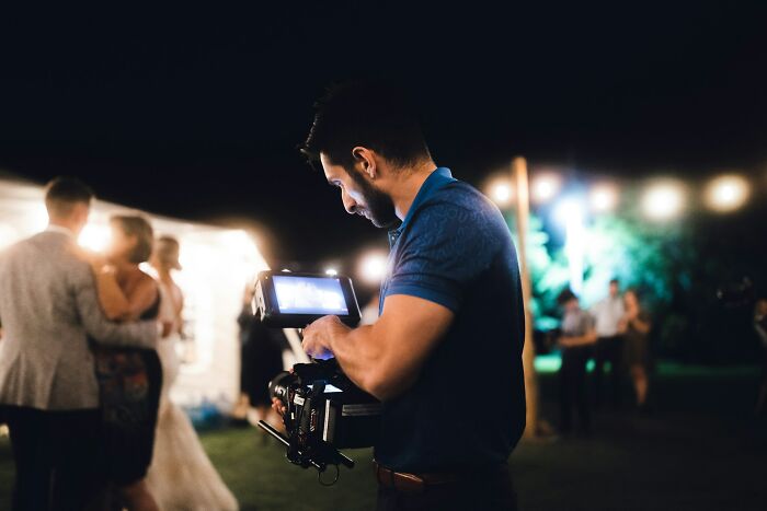 Wedding videographer filming couple dancing outdoors
