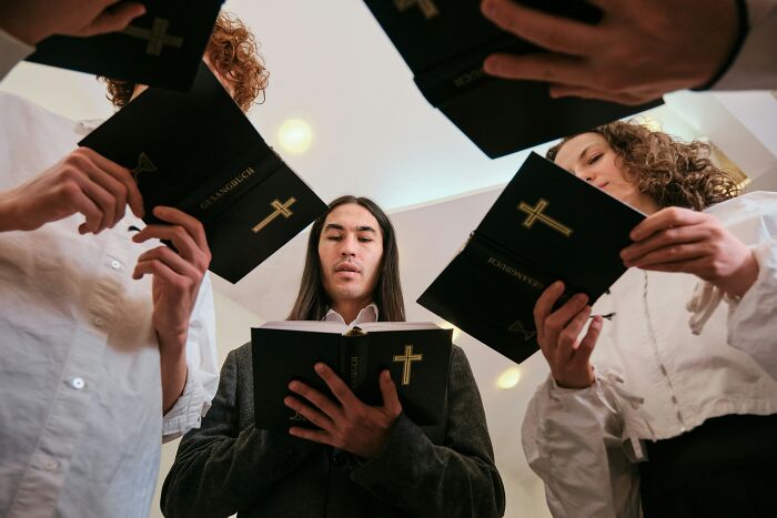 Group of people holding Bibles during cult gathering