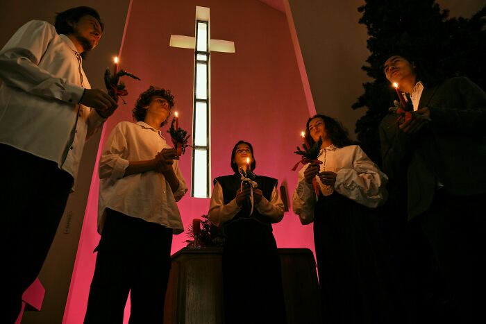 Group holding candles under a lit cross symbolizing hope after cult escape