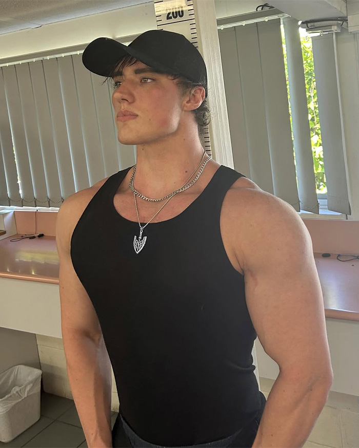 Looksmaxxer androgenic man posing in black tank top and cap