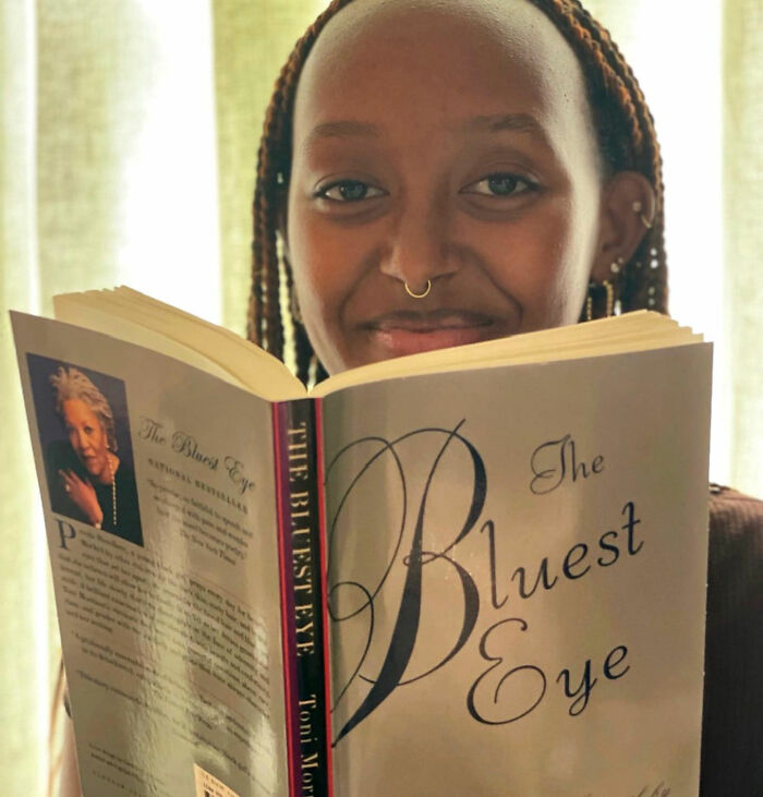 Zahara Jolie lendo o livro The Bluest Eye em uma sala bem iluminada Zahara Jolie lendo o livro The Bluest Eye em uma sala bem iluminada
