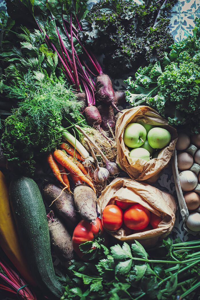 Fresh vegetables including carrots, beets, apples, and greens in a basket