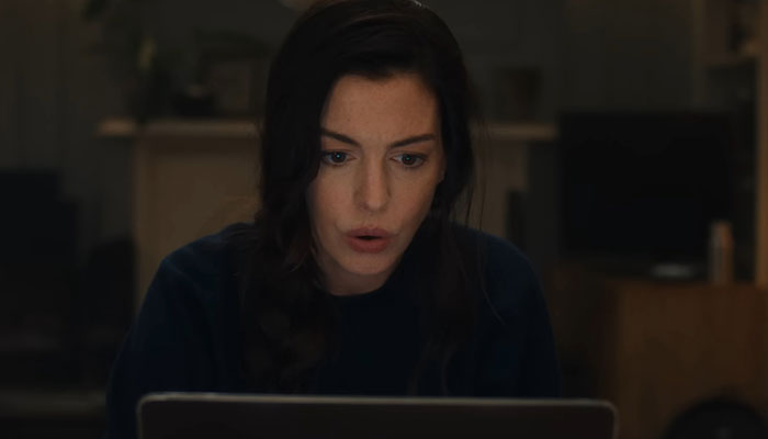 Anne Hathaway focused on laptop screen indoors