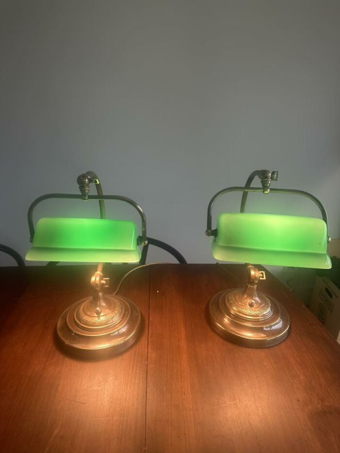 Pair of vintage secondhand green glass banker lamps with brass bases on wood table